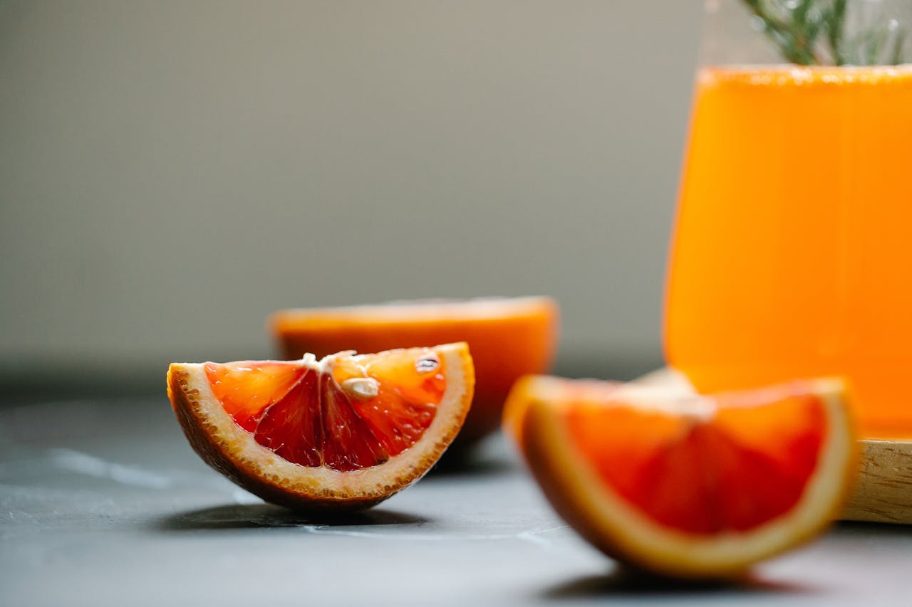 An orange drink and slices of oranges on a table