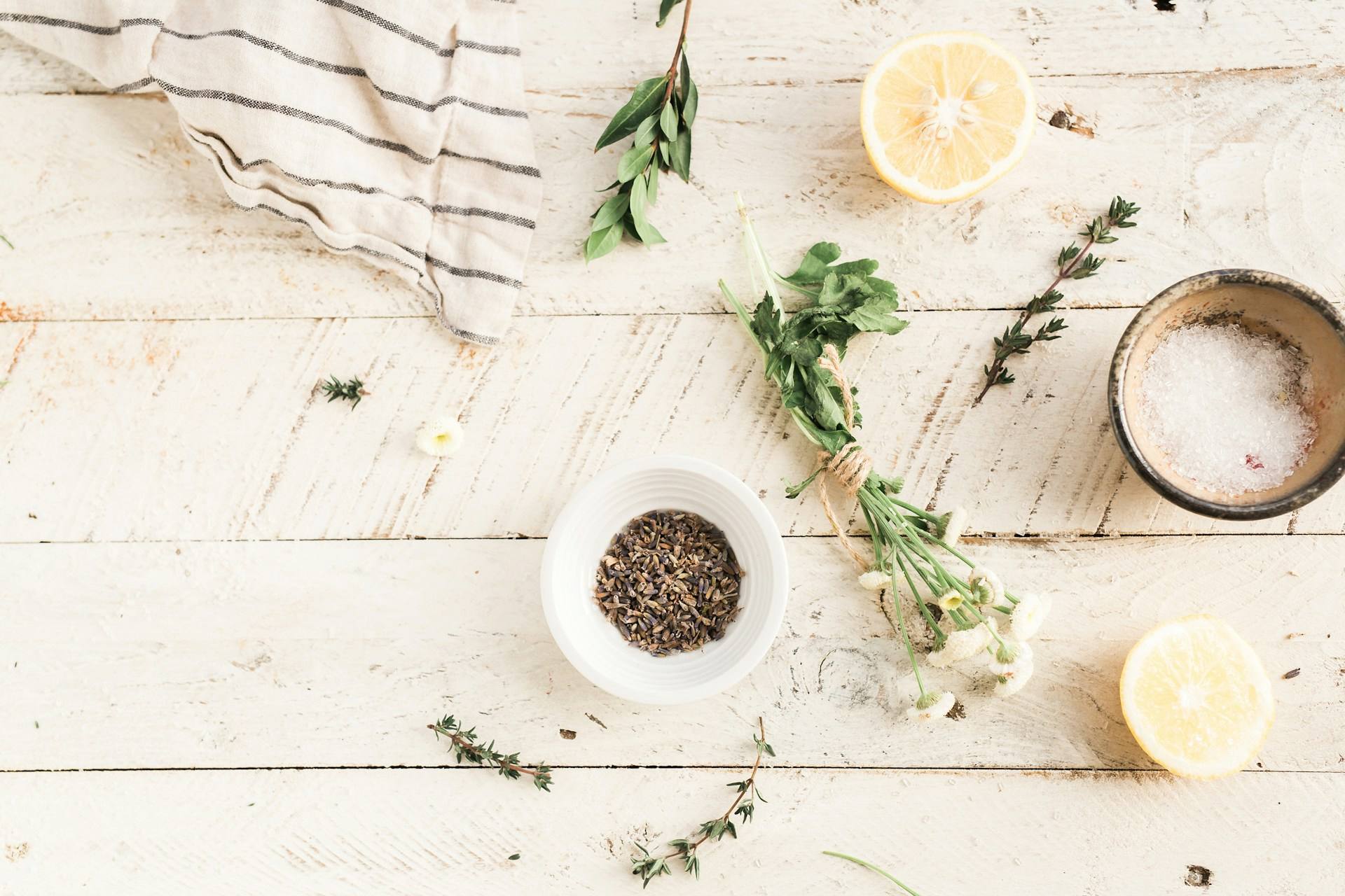 A shot of a wooden table showing different healthy ingredients, such as lemons, herbs, salt, and black pepper