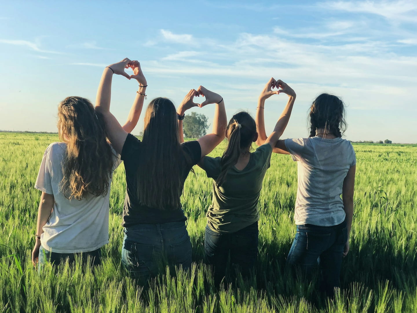 a group of women in a field making heart hand shapes